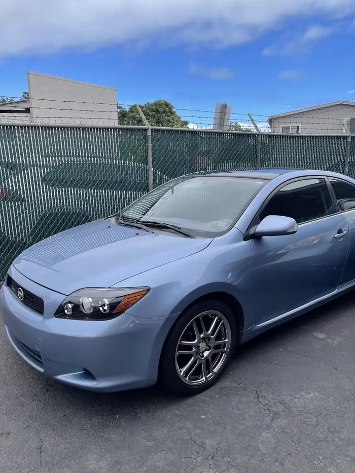 Light blue Scion tC after repaint and detail, parked outside the shop